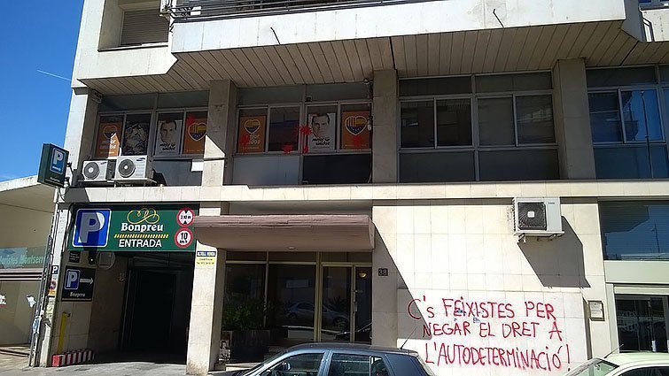 Pla general dels vidres de la seu de Ciutadans de Lleida tacats de color vermell i de la pintada apareguda a l'exterior de l'edifici. Imatge del 6 d'abril del 2017. (Horitzontal)