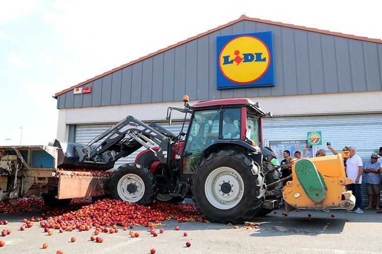 Un tractor amb pala que aboca nectarines des d'un remolc a la porta del LIDL