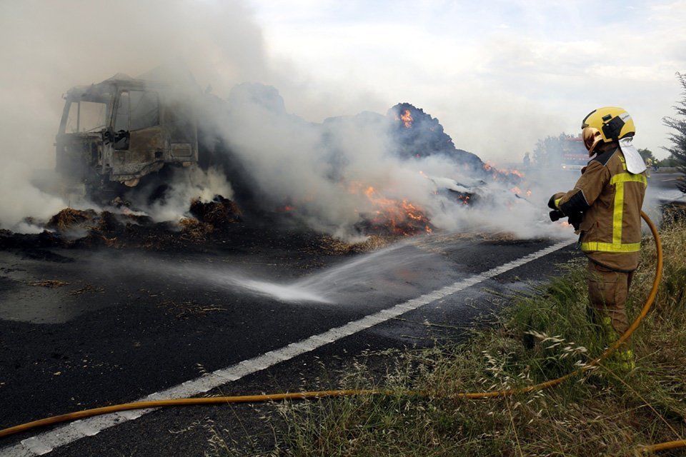 Un bomber amb la mànega d'aigua ruixant una màquina