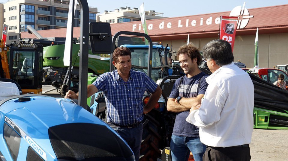 Pla mig on es poden veure dos visitants a la Fira de Sant Miquel de Lleida consultant a un expositor de tractors, el 27 de setembre de 2018. (Horitzontal)