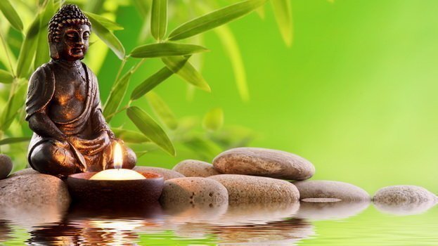 Buddha in meditation with burning candle,bamboo leaf and zen stones.