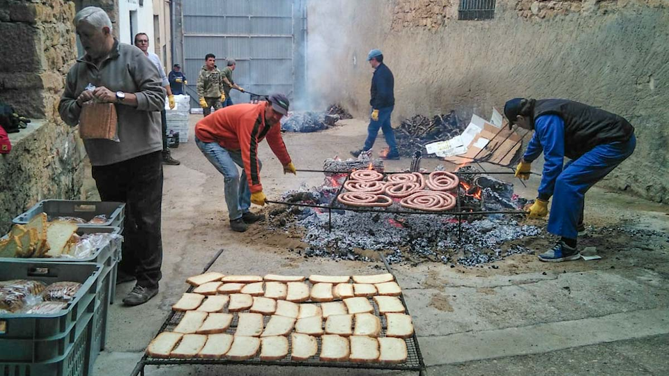 Imatge de la preparació de l'esmorzar popular amb pa torrat, llonganissa i cansalada a la Fira de l'Oli de la Juncosa
