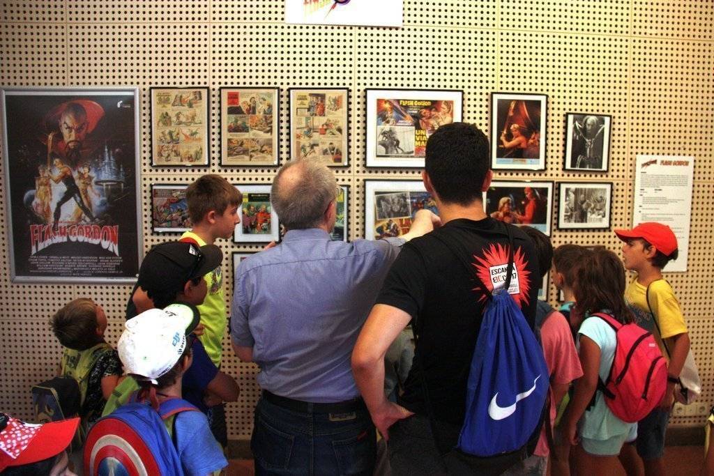 Pla mitjà del cinèfil i col·leccionista Josep Benavent explicant a diversos participants del casal d'estiu de la Seu d'Urgell alguns dels còmics de l'exposició 'Herois i superherois'. Imatge del 6 d'agost de 2019 (Horitzontal).