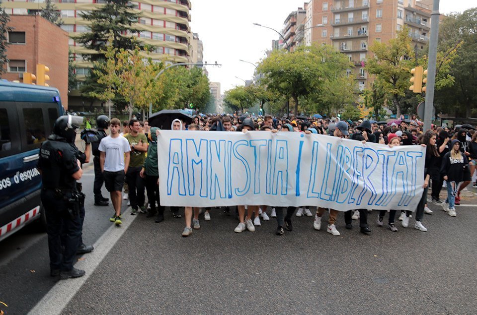 Els participants en la manifestació de Lleida de rebuig a la sentència del Suprem, passant a prop de la comissaria de la policia de l'Estat, custodiada pels Mossos el 14 d'octubre del 2019. (Horitzontal)