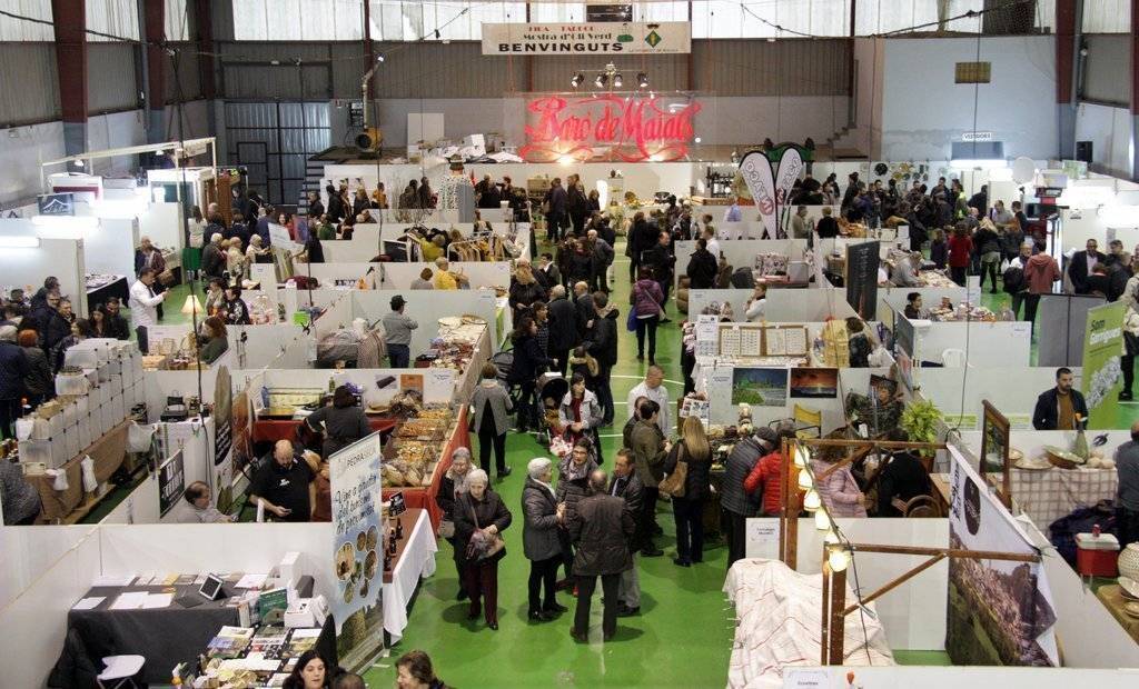 Pla general de les parades instal·lades a l'interior del pavelló de Maials, amb visitants recorrent els passadissos, en el marc de la 21a Fira de l'Oli Verd, el 18 de novembre de 2018 (Horitzontal).