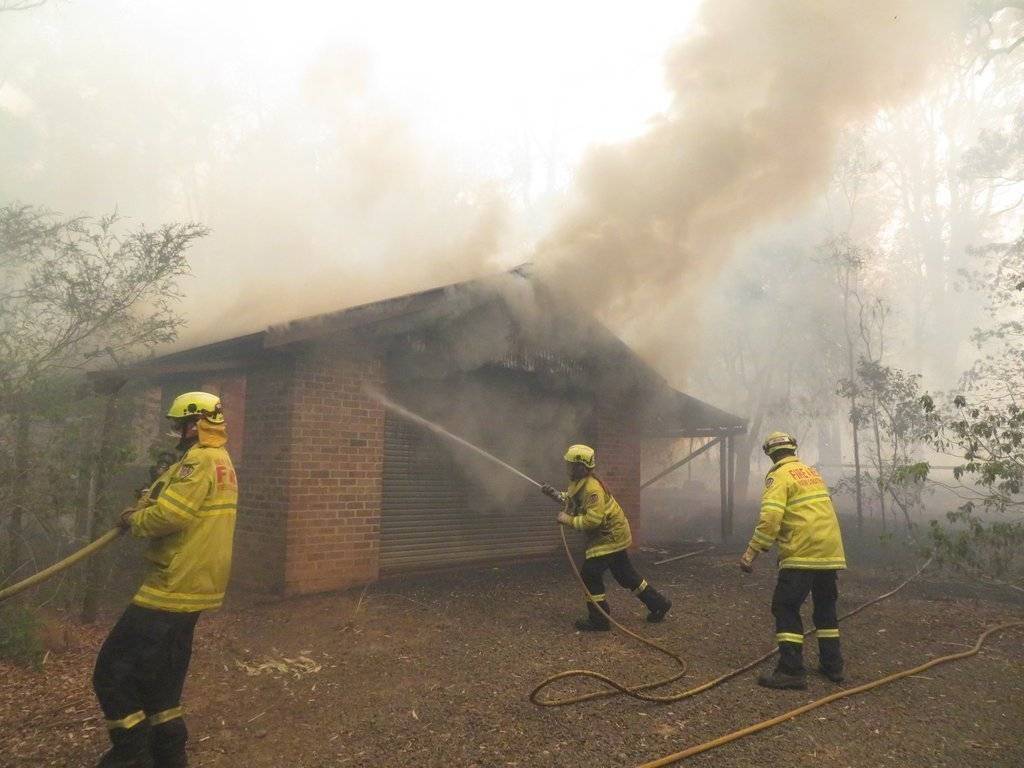 Fire and Rescue NSW firefighters work to save a burning house in McLeay Road hit by a direct impact from the Green Wattle Creek bushfire at Werombi in South West Sydney - Helitak430