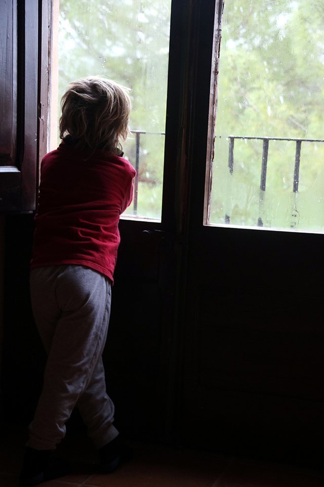 Un nen observa les volves de neu des de la finestra de casa