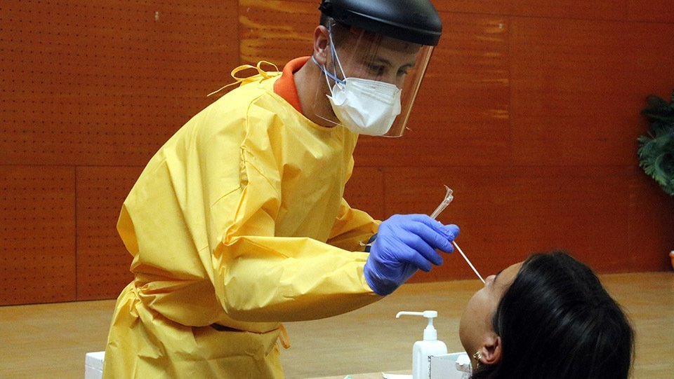 Pla mitjà on es pot veure un sanitari fent una prova PCR a un veí del barri de Balàfia de Lleida en el marc del cribratge massiu per trobar asimptomàtics de covid-19, el 28 d'agost de 2020. (Horitzontal)