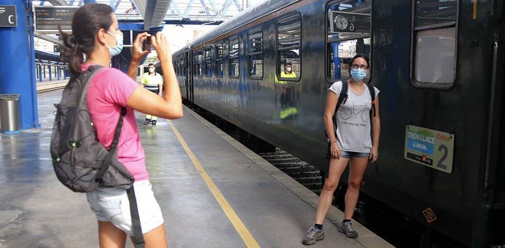 Pla obert d'una noia fent una fotografia a una amiga seva davant el Tren dels Llacs a l'estació de Lleida,  el 29 d'agost de 2020. (Horitzontal)p