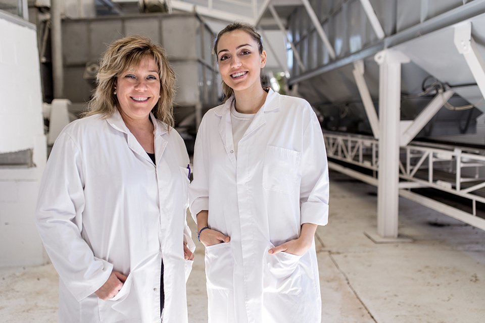 Two women with white coat working in a factory