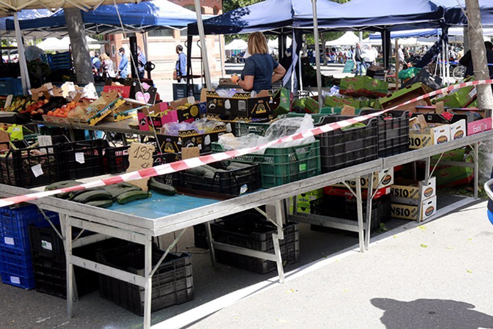 Pla obert d'un client d'una de les parades del mercat del Barris Nord que guarda la distància de seguretat mentre es atès, el 2 de maig de 2020. (Horitzontal)