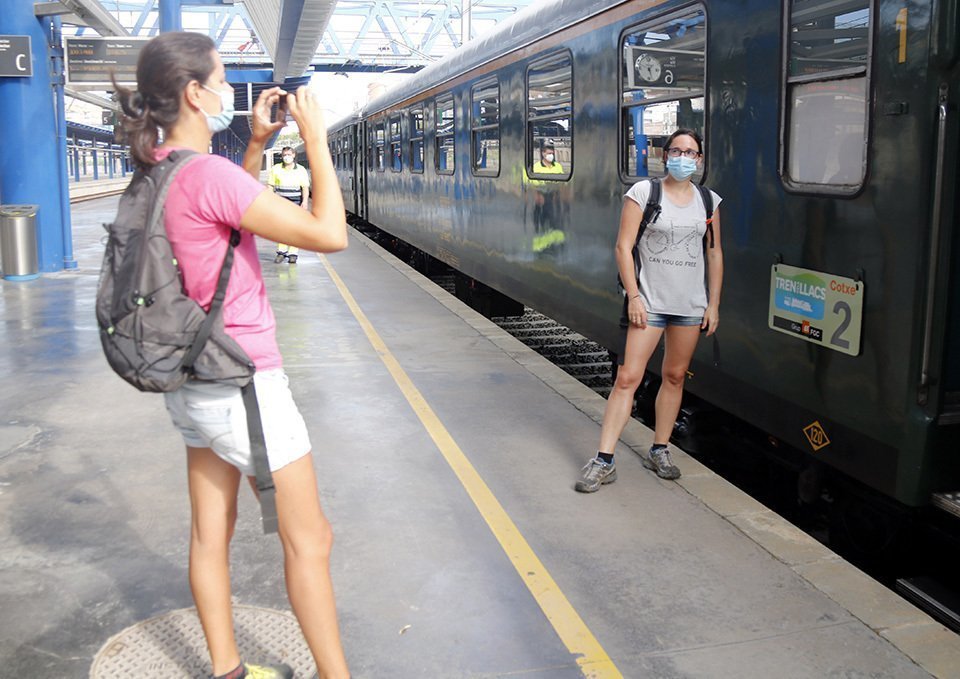Pla obert d'una noia fent una fotografia a una amiga seva davant el Tren dels Llacs a l'estació de Lleida, el 29 d'agost de 2020. (Horitzontal)p