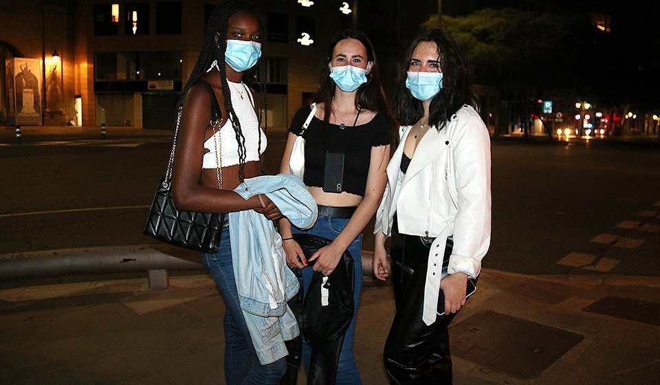Pla mitjà d'un grup de tres amigues que han sortit per Lleida a celebrar la fi del toc de queda nocturn pocs minuts després de la mitjanit, el 9 de maig de 2021. (Horitzontal)