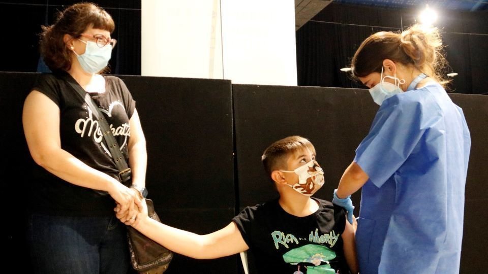 Laura CortésPla mig d'un nen vacunant-se a Tàrrega, mentre la seva mare li agafa la mà. Imatge del 4 d'agost de 2021. (Horitzontal)